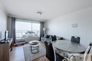 a living room with a table and a couch at Le Panoramique Marin- 2Ch in Bray-Dunes