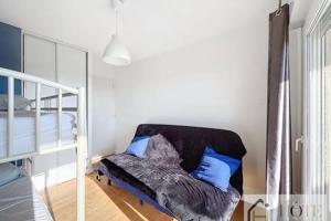a bedroom with a bed and a couch with blue pillows at Le Panoramique Marin- 2Ch in Bray-Dunes