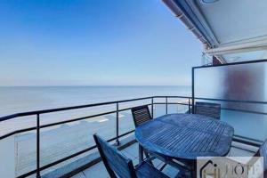 a table and chairs on a balcony overlooking the ocean at Le Panoramique Marin- 2Ch in Bray-Dunes