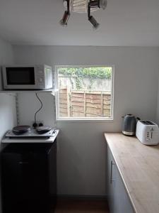a kitchen with a stove and a window in it at Delightful cosy cabin in Margate