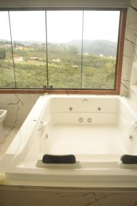 a bath tub in a bathroom with a window at Suítes e Loft do Tião in Lavras Novas +75 photos