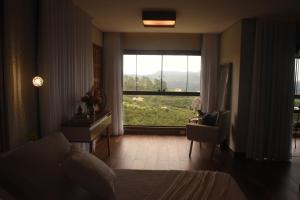 a bedroom with a bed and a large window at Suítes e Loft do Tião in Lavras Novas