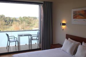 a hotel room with a bed and a window with a table and chairs at Hotel Dom Afonso - Monção in Monção