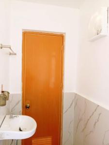 a bathroom with a sink and a wooden door at Gregorio's Inn in San Vicente