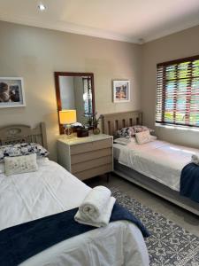 a bedroom with two beds and a mirror at Picasso's Cottage in Gqeberha