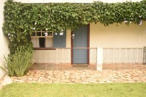a house with a blue door and ivy at Suítes e Loft do Tião in Lavras Novas