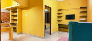 a yellow room with a desk and a television at Aadhya guest house in Tiruvannāmalai