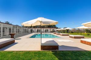 a swimming pool with an umbrella and some benches and a pool at Agriturismo Agricola Chiani in Melendugno +34 photos