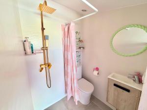 a bathroom with a pink shower curtain and a toilet at Habitación con baño y cocina in Caudiel