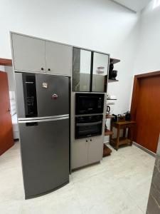 a kitchen with a refrigerator and a microwave at Refúgio Rossa in Xangri-lá