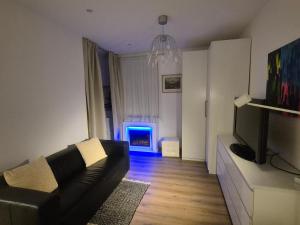 a living room with a black couch and a tv at Dein Zuhause am See in Millstatt