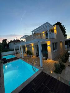 a house with a swimming pool in front of it at Seaside Pool Villas by BookVillaEU in Nea Kallikrateia