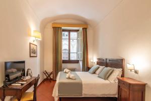 a bedroom with a bed and a desk and a television at Hotel Cimabue in Florence