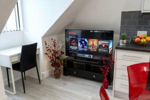 a living room with a television and a table with a desk at Rosey Lodge -1Bedroom Cousy Flat - Parking, Netflix, WIFI - Close to Blenheim Palace & Oxford - F5 in Oxford