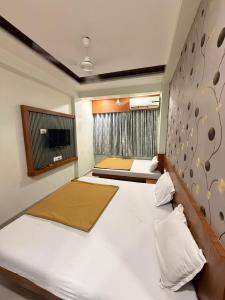 a bedroom with two beds and a tv on the wall at Hotel Sumeet Palace in Shirdi +7 photos