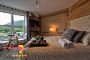 a bedroom with a large bed with a table and a window at Lakeside Gateway 4 Spa Sauna Firepit in Sainte Brigitte de Laval
