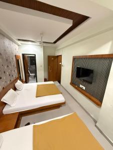 a room with two beds and a tv in it at Hotel Sumeet Palace in Shirdi