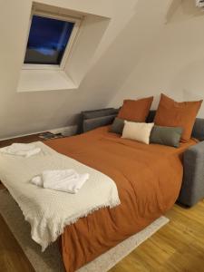 a bedroom with a bed with an orange blanket and a window at Le perchoir de Pibri - Les apparts de Maddy in Meyssac