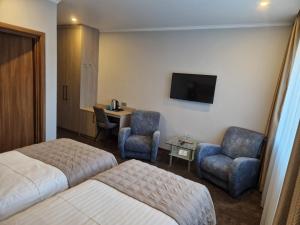 a hotel room with two beds and a desk and chairs at Olympus Hotel in Kaunas