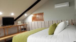 a bedroom with a white bed with green pillows at Corazón Del Café Hotel Boutique in Comitán
