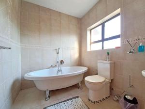 a bathroom with a tub and a toilet and a window at Tuscany By The Sea in Port Edward +70 photos