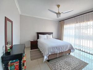 a bedroom with a bed with a ceiling fan and a window at Tuscany By The Sea in Port Edward