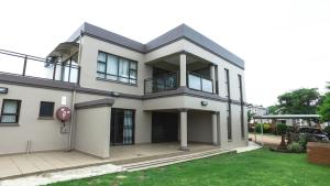 a large white house with a balcony at Tuscany By The Sea in Port Edward