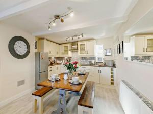 a kitchen with a table and a clock on the wall at 3 Bed in Holmfirth oc-91797 in Holmfirth