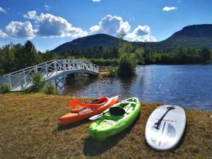 three kayaks on the shore of a river with a bridge at Lakeside Getaway #5 Spa Sauna Firepit in Sainte Brigitte de Laval