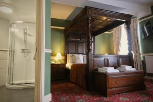 a bedroom with a canopy bed and a shower at The Wynnstay in Machynlleth