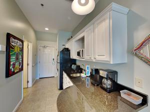 a kitchen with white cabinets and a black refrigerator at Inn at Seacrest #203 - 30A Get-A-Way in Rosemary Beach