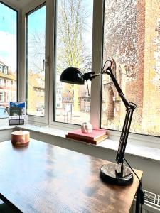 a desk with a lamp sitting on a book in front of a window at Der Stader Turmblick in Stade