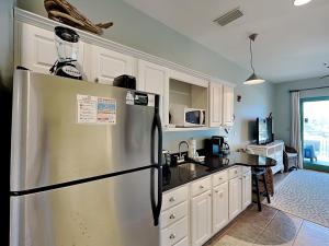 a kitchen with a stainless steel refrigerator and white cabinets at Inn at Seacrest #203 - 30A Get-A-Way in Rosemary Beach