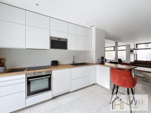 a kitchen with white cabinets and a red chair at L'Instant Elégant - Plage à 100m in Bray-Dunes
