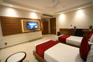 ein Hotelzimmer mit zwei Betten und einem Flachbildfernseher in der Unterkunft Rohika AAU-IGH in Guwahati