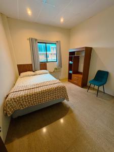 a bedroom with a bed and a blue chair at Kicker House in Puerto Baquerizo Moreno