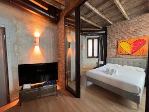 a bedroom with a bed and a tv and a brick wall at Emmeloft I Orange Moon - Vibrant Modern Luxury Loft Milan in Milan
