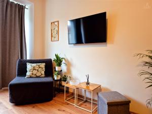 a living room with a chair and a tv on the wall at City Center Apartments - Moderna Brno Římské náměstí IV in Brno