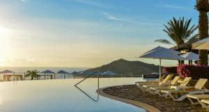 a pool with chairs and umbrellas and the ocean at Pueblo Bonito Sunset Beach Owners Studio Suite, REQUEST DATES see by Clay & Lisa in Cabo San Lucas