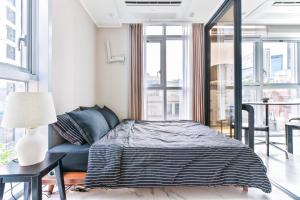 a bedroom with a bed with a blue couch and windows at Balance Seoul Stay in Seoul