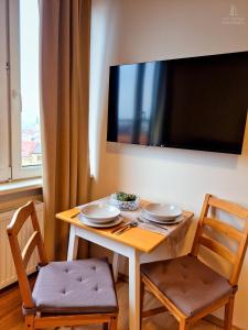 a table with two chairs and a television on a wall at City Center Apartments - Moderna Brno Římské náměstí V in Brno
