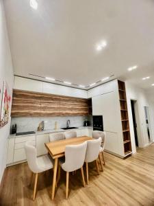 a kitchen with a wooden table and white chairs at Veranda Apartment, Green Coast in Palasë