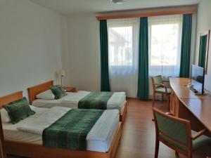 a hotel room with two beds and a desk and a computer at SDG Családi Hotel és Konferencia Központ in Balatonszárszó