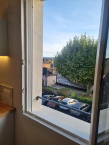 a window with a view of cars parked on a street at Le perchoir de Pibri - Les apparts de Maddy in Meyssac