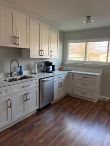 a kitchen with white cabinets and a wooden floor at Lonnie in Westland