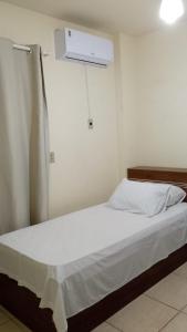 a bedroom with a bed with a white bedsheet at Praias do Sul in Cabo Frio