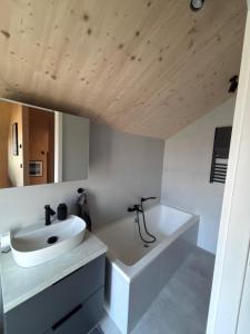 a white bathroom with a sink and a tub at Ferienhaus Sonnenwasser am Partwitzer See in Klein Partwitz