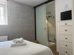 a bedroom with a bed with towels and a shower at ALAIA Mundaka in Mundaka
