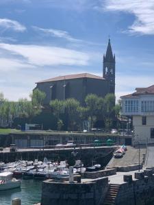 a group of boats docked in a harbor with a clock tower at ALAIA Mundaka in Mundaka