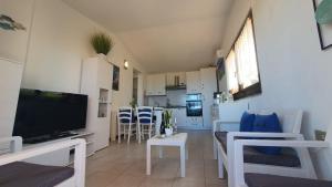 a living room with a flat screen tv and a kitchen at Poolvilla Bellavista - Vista Panoramica sul Mare in Costa Paradiso